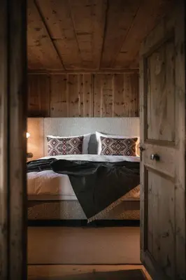 a bedroom with a large bed with a wooden ceiling at Felder Alpin Lodge in Villandro