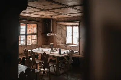 a dining room with a table and chairs and windows at Felder Alpin Lodge in Villandro
