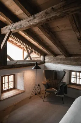 a room with a chair and a lamp and windows at Felder Alpin Lodge in Villandro