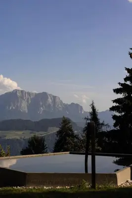 a swimming pool with mountains in the background at Felder Alpin Lodge in Villandro