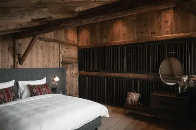 a bedroom with a large bed and wooden walls at Felder Alpin Lodge in Villandro