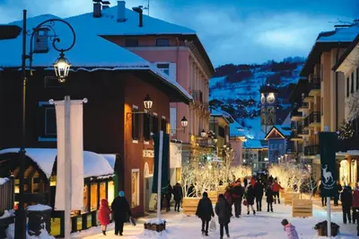a group of people walking down a city street in the snow at La Finestra sui Monti - Alpine Stay Apartments in Cavalese
