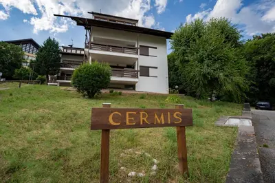 a sign in the grass in front of a building at La Finestra sui Monti - Alpine Stay Apartments in Cavalese