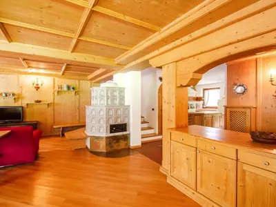 a living room with a wooden ceiling and a stove at Chalet Cesa Galadriel-3 by Interhome in Penia