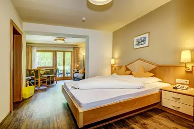 a bedroom with a large bed and a living room at Alpenhof Lodge in Saltusio