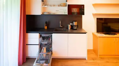 a small kitchen with white cabinets and a dishwasher at Alpenhof Lodge in Saltusio