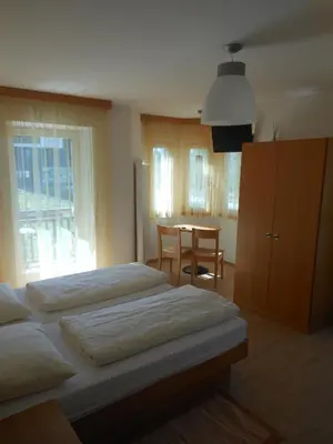 a bedroom with two beds and a table and a chair at Ottenkellerhof in Bolzano