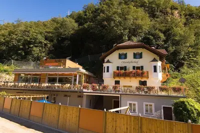a white building with a balcony on top of a fence at Ottenkellerhof in Bolzano