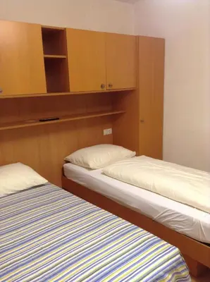 two beds in a small room with wooden cabinets at Ottenkellerhof in Bolzano