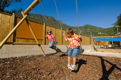 two children playing on a swing set at a playground at Ottenkellerhof in Bolzano