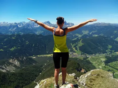 a woman standing on top of a mountain with her arms outstretched at Agriturismo La Flu in San Martino in Badia