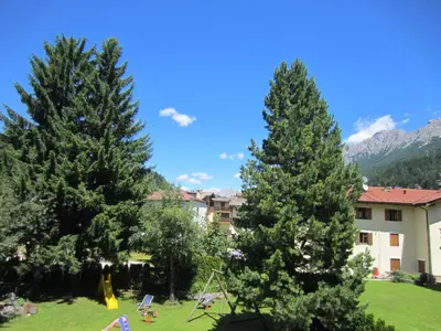a group of pine trees in a yard with a building at Condominio Zorzi in Moena