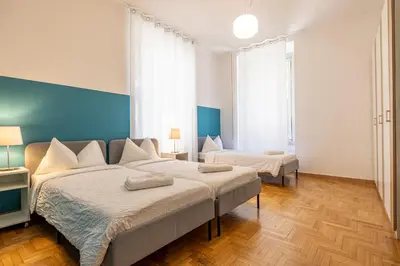 a bedroom with two beds and a blue wall at Mia Rooms - Room with Private Bath Bolzano Center in Bolzano