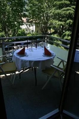 a table with wine glasses sitting on a balcony at Ferienwohnung Thermen in Merano