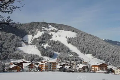 a ski resort with a snow covered mountain at Pension Arnica B&B in San Vigilio Di Marebbe