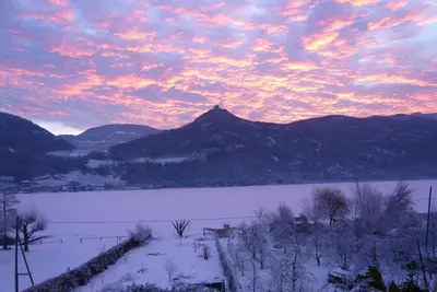 a sunset over a snowy field with a mountain at Ferienwohnung Seespiegel direkt am Kalterer See in Caldaro