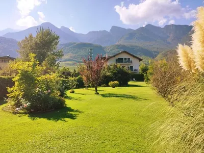 a yard with a house and mountains in the background at Ferienwohnung Seespiegel direkt am Kalterer See in Caldaro