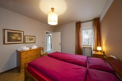 a bedroom with a red bed and a window at Villa Ginestra 3 in Moena