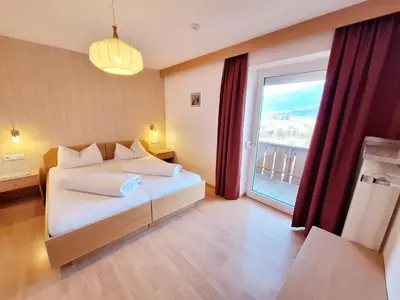 a bedroom with a bed and a large window at Hotel Pörnbacher in Valdaora