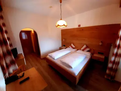 a bedroom with a large bed with a wooden headboard at Hotel Pörnbacher in Valdaora