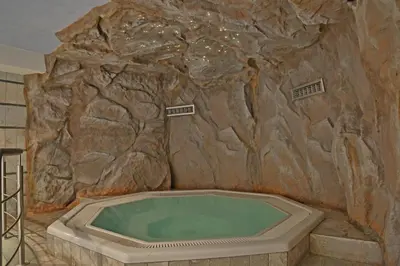 a bath tub in a room with a rock wall at Hotel Pörnbacher in Valdaora