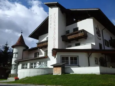 a large white building with a tower at Hotel Pörnbacher in Valdaora