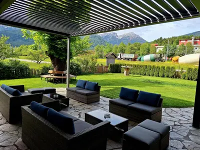 a patio with couches and chairs and a lawn at Hotel Pörnbacher in Valdaora