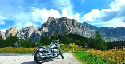 a motorcycle parked on a road in front of a mountain at Café Rudi Living in Parcines