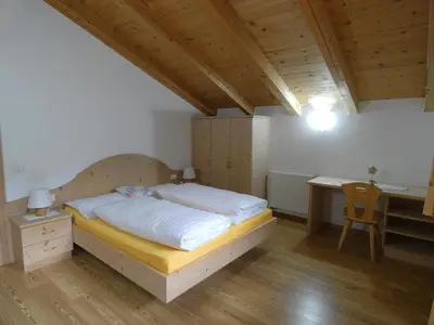 a bedroom with a bed and a desk and a table at Casa Gogn in San Vigilio Di Marebbe