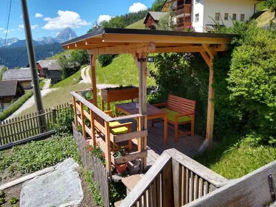 a wooden gazebo with a table and chairs at Casa Gogn in San Vigilio Di Marebbe