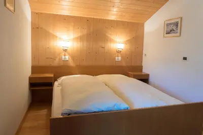 a bed in a room with two lights on the wall at Ciasa Torneri in San Vigilio Di Marebbe
