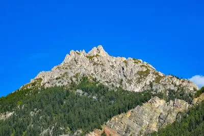 a rocky mountain with trees and a blue sky at Cone da Val in San Vigilio Di Marebbe