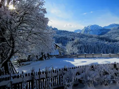 a fence covered in snow with mountains in the background at Cone da Val in San Vigilio Di Marebbe