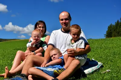 a family sitting on the grass in a field at Cone da Val in San Vigilio Di Marebbe