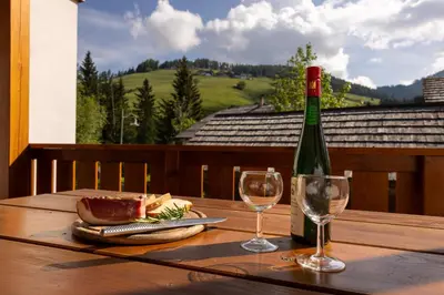 a bottle of wine sitting on a wooden table with two glasses at Cone da Val in San Vigilio Di Marebbe