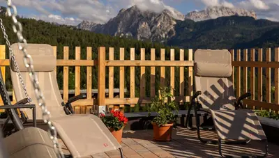 two chairs sitting on a porch with mountains in the background at Cone da Val in San Vigilio Di Marebbe