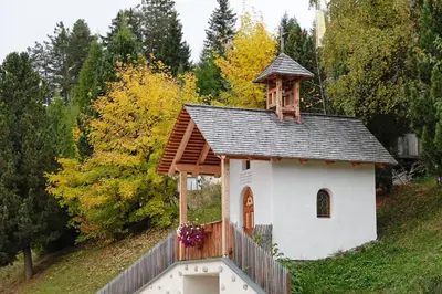a small white chapel with a roof on a hill at Agriturismo Soleseid in San Vigilio Di Marebbe