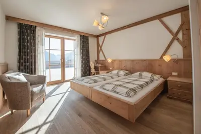 a bedroom with a large bed and a chair at Agriturismo Soleseid in San Vigilio Di Marebbe
