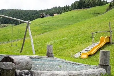 a playground with a yellow slide on a hill at Messnerhof, Durnholz in Valdurna