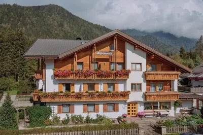 a building with a balcony with flowers on it at Residence Alpenrose in Rasùn di Sotto