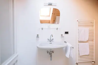 a white bathroom with a sink and a mirror at Residence Alpenrose in Rasùn di Sotto