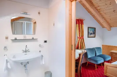 a bathroom with a sink and a blue chair at Residence Alpenrose in Rasùn di Sotto