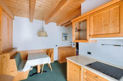 a kitchen with wooden cabinets and a table at Residence Alpenrose in Rasùn di Sotto