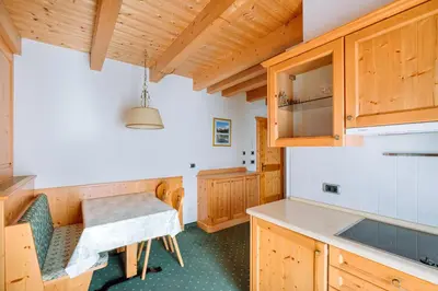 a kitchen with wooden cabinets and a table at Residence Alpenrose in Rasùn di Sotto
