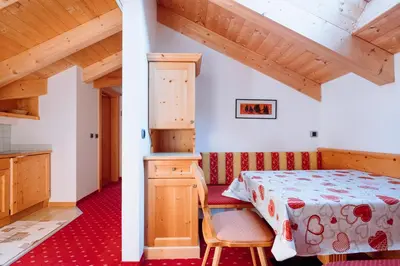 a bedroom with a bed and a chair in a room at Residence Alpenrose in Rasùn di Sotto