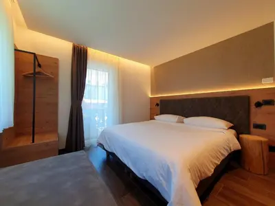 a bedroom with a large white bed and a window at Casa Il Giardino in Pozza di Fassa