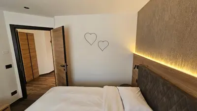 a bedroom with a bed with two hearts on the wall at Casa Il Giardino in Pozza di Fassa