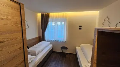 a small room with two beds and a window at Casa Il Giardino in Pozza di Fassa