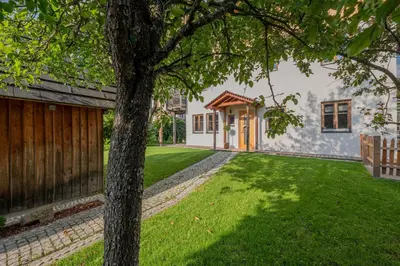 a house with a tree in front of a yard at Eco Chalet Olival in Braies