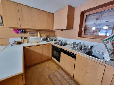a kitchen with wooden cabinets and a sink and a dishwasher at Col Rodella - Canazei in Canazei